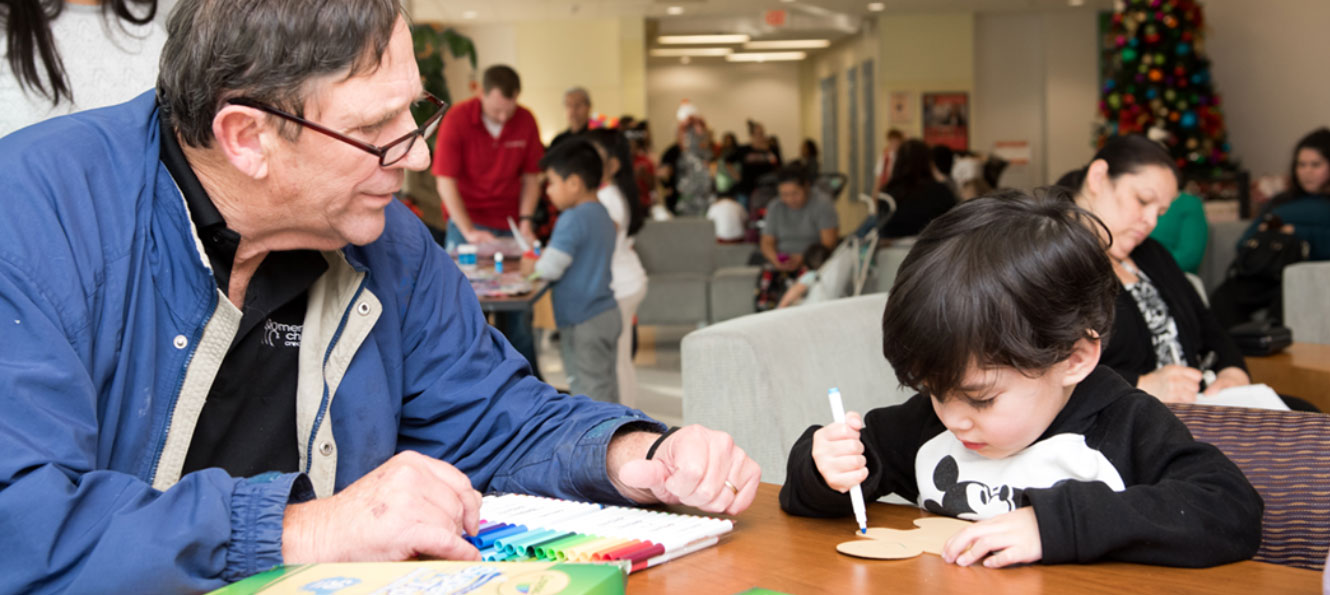 a Members Choice employee volunteers with a young child coloring at a community event